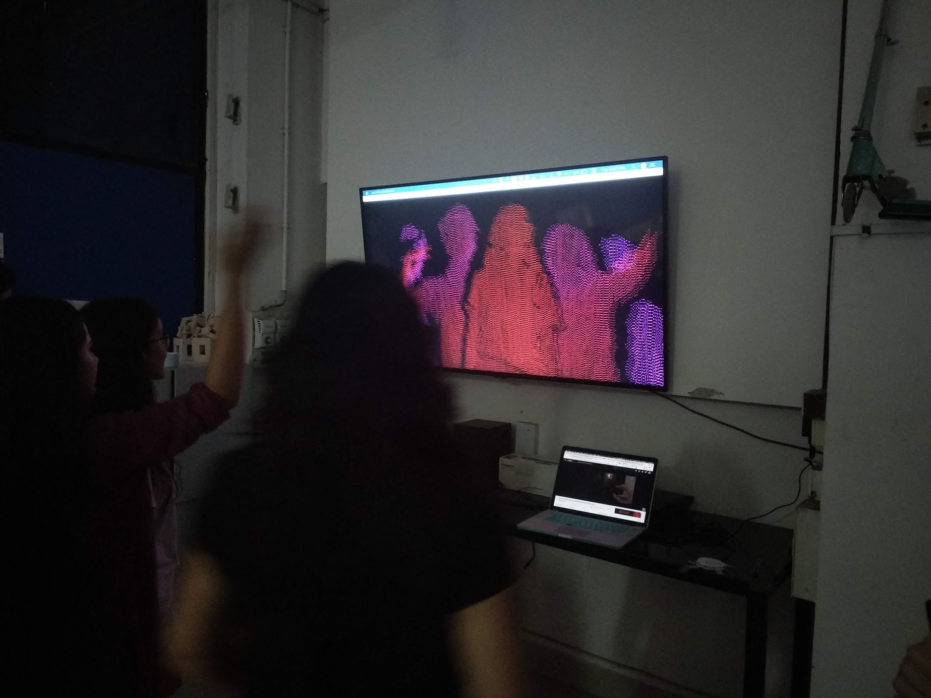 People standing in front of a TV running the dots installation.