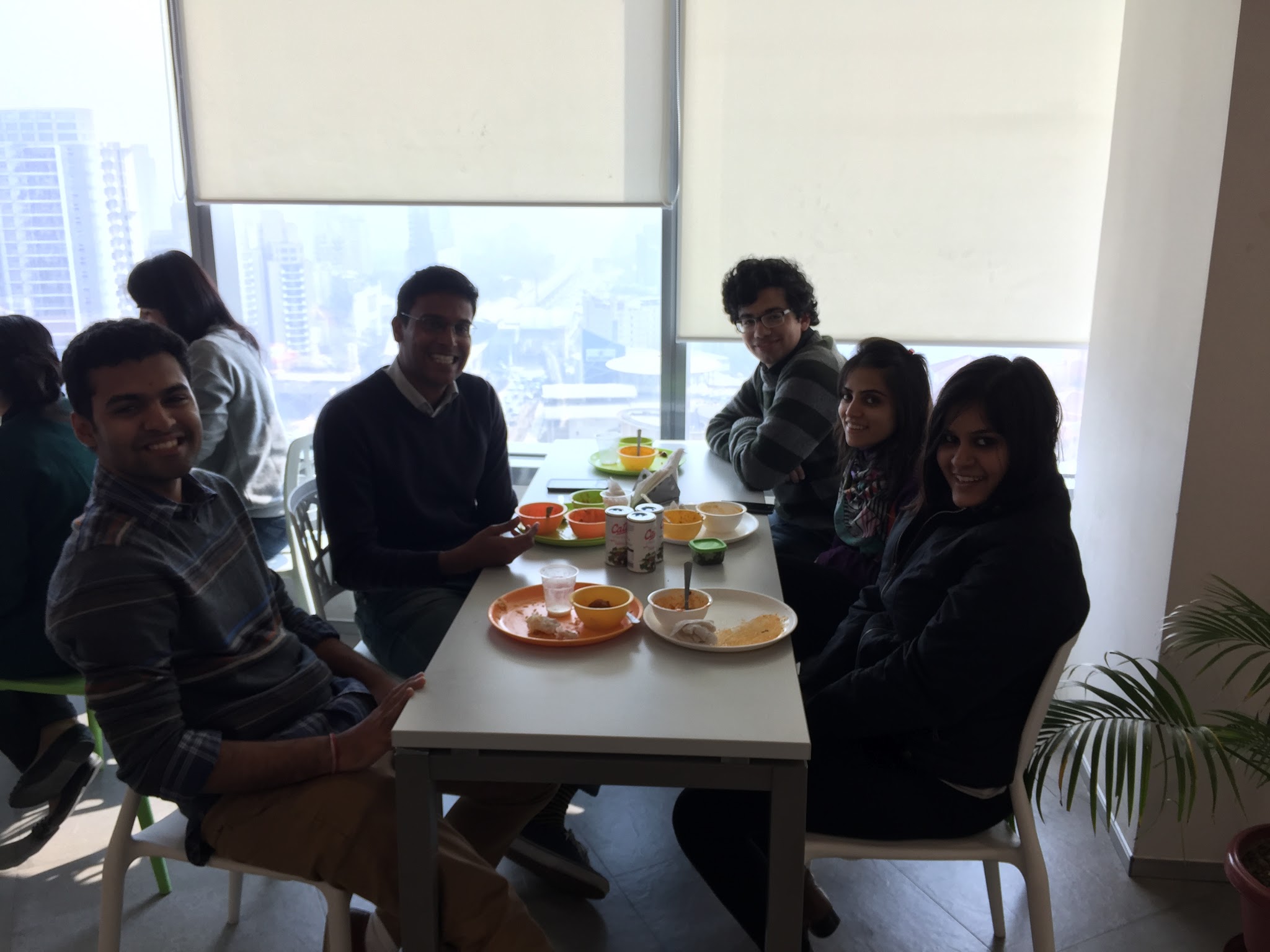 Cafeteria table with food and people sitting around it.